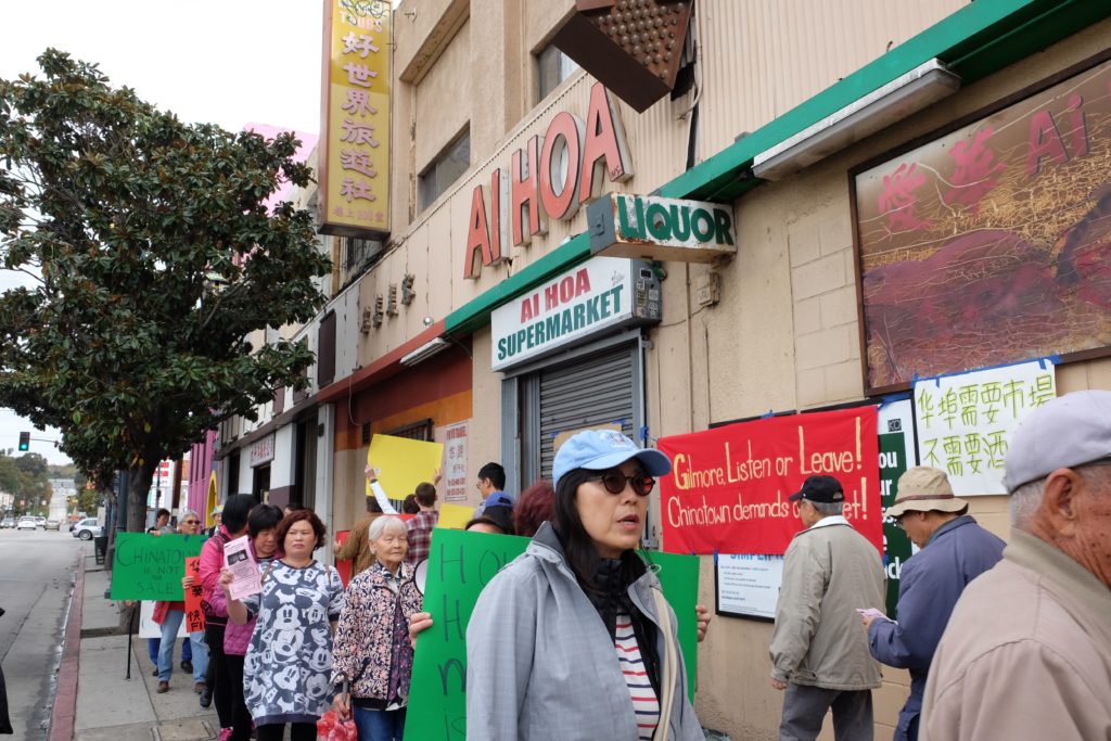 Protestors demonstrating against gentrification hold up signs in English, Cantonese, and Spanish after Ai Hoa, the last full-service grocery store in Chinatown, was priced out of the neighborhood.