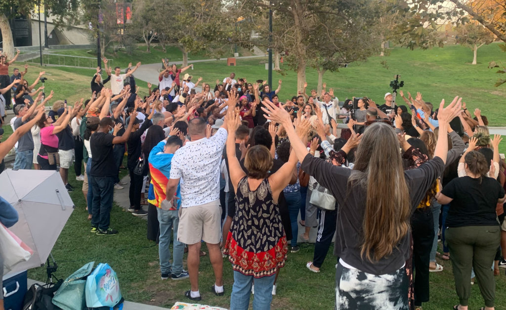 A crowd holds hands to the sky during an open air session of Kathryn Krick's ministry in Los Angeles. 